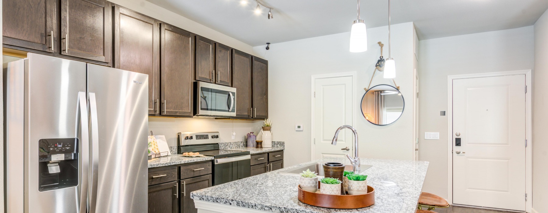 Model kitchen at our apartments in Midland, TX, featuring wood grain floor paneling and a kitchen island.
